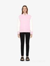 Person wearing a pink and white sleeveless top with black pants on a white background